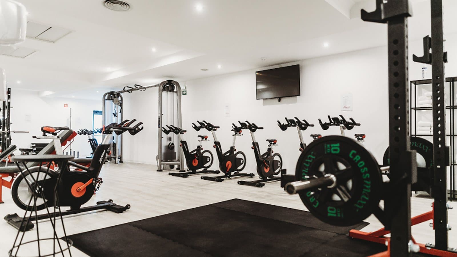 Modern gym floor with spin bikes and a loaded squat rack, the kind of space a protein counter or vending machine serves